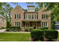 Charming brick two-story home featuring manicured landscaping, black shutters, and a covered front porch at 109 Aspenridge Dr, Holly Springs, NC 27540