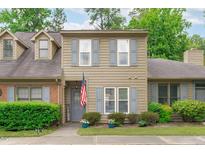 Charming two-story townhouse with a welcoming front entrance, complemented by lush greenery and an American flag at 11 Stone Village Ct, Durham, NC 27704