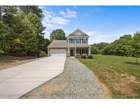 Charming two-story home featuring a brick and siding facade, attached garage, and a well-maintained front yard at 2021 W Front St, Burlington, NC 27215