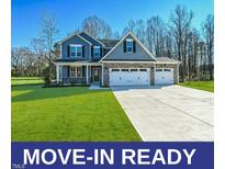 Charming two-story home featuring blue siding, stone accents, and a three-car garage on a manicured lawn at 21 Abingdon Farms Dr, Selma, NC 27576
