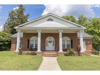 Charming brick home featuring a columned front porch and a well-manicured lawn at 219 E Nash St, Spring Hope, NC 27882