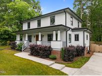 Charming two-story home featuring a welcoming front porch, manicured lawn, and beautiful landscaping at 2551 Drake Ave, Durham, NC 27705