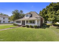 Charming two-story home with a screened-in porch, lush lawn, and mature trees at 413 E Center St, Nashville, NC 27856