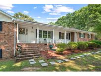 Charming brick home with a covered front porch, landscaped yard, and stepping stones pathway at 5414 Ventoria Rd, Durham, NC 27712