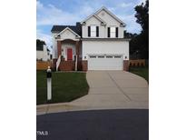 Charming two-story home boasts a well-manicured lawn, brick accents and a bright red front door at 8600 Colville Ct, Raleigh, NC 27617