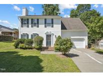 Charming two-story home featuring a well-manicured lawn, white siding, black shutters, and an attached garage at 105 Leacroft Way, Durham, NC 27703