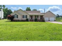 Charming home with a well-maintained lawn, a covered porch, and an attached two-car garage at 110 Westlake Dr, Wendell, NC 27591