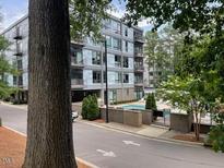 Modern condo building featuring a swimming pool, balcony, and lush trees around at 1300 St Marys St # 402, Raleigh, NC 27605