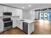 Modern kitchen features stainless steel appliances, white cabinetry, and a quartz countertop island at 1300 St Marys St # 402, Raleigh, NC 27605