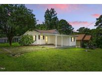 Charming one-story home featuring a covered porch, well-maintained lawn, and lovely landscaped surroundings at 16 S Church, Coats, NC 27521