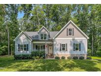 Charming home featuring tidy landscaping, a welcoming front porch, and a classic American flag at 167 Sequoia Dr, Timberlake, NC 27583