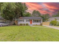 Charming single-story home featuring a well-maintained lawn and an inviting orange front door at 1708 Forest Rd, Durham, NC 27705