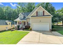 Inviting home with a two-car garage and a neatly manicured lawn, enhanced by mature trees in the background at 200 Holly Branch Dr, Holly Springs, NC 27540