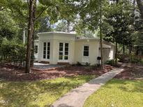 Charming home featuring a light yellow brick exterior, elegant white trim, and lush landscaping at 2428 Perkins Rd, Durham, NC 27705