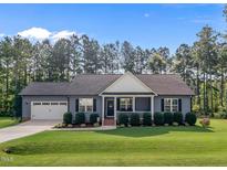 Charming single-story home with a well-manicured lawn, attached garage and inviting front porch at 244 Lasswade Ct, Zebulon, NC 27597
