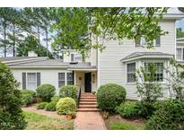 Charming home with a brick walkway leading to the entrance, complemented by lush landscaping and mature trees at 384 Lyndfield Cl W, Pittsboro, NC 27312