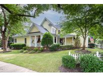 Charming yellow two-story home featuring a welcoming front porch and beautifully landscaped front yard at 4001 Falls River Ave, Raleigh, NC 27614