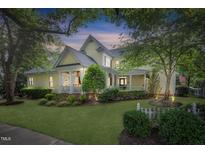 Inviting two-story home with a charming front porch, beautiful landscaping, and mature trees at 4001 Falls River Ave, Raleigh, NC 27614