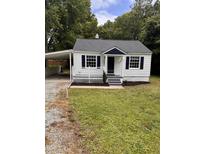 Charming home featuring a quaint front porch, white siding, and a convenient carport at 603 S Third St, Mebane, NC 27302