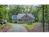 Charming home with a welcoming front porch and solar panels nestled among lush trees at 8226 Mcarthur Park Dr, Efland, NC 27243