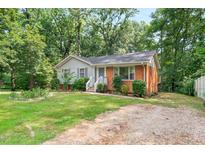 Charming brick and siding home with a well-maintained front yard and a gravel driveway at 106 Lattimore Ln, Durham, NC 27713