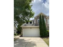 Stone and siding exterior with a white garage door, manicured lawn, and mature evergreens at 1090 Indigo Ridge Pl, Cary, NC 27519