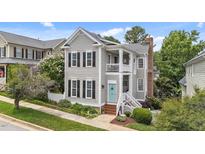 Charming two-story home featuring gray siding, black shutters, a welcoming porch, and manicured landscaping at 124 Kingsport Rd, Holly Springs, NC 27540