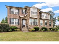 Inviting two-story home with brick and stone facade, manicured lawn, and lovely landscaping at 150 Saint Mellion St, Raleigh, NC 27603