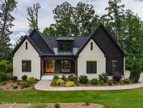 Charming, modern home with a combination of white-painted brick and black accents and lush front yard landscaping at 153 W Beech Slope Ct, Chapel Hill, NC 27517