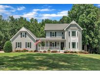 Charming two-story home featuring a welcoming front porch, a well-manicured lawn, and lush, mature landscaping at 171 St. Jiles Dr, Clayton, NC 27520