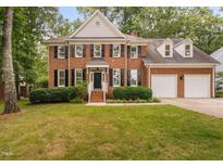 Traditional two-story brick home featuring black shutters and a well-manicured lawn at 202 Stoneleigh Dr, Cary, NC 27511