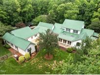 Stunning aerial view of sprawling home with a green metal roof surrounded by lush greenery and mature trees at 300 Oak Ridge Dr, Hillsborough, NC 27278