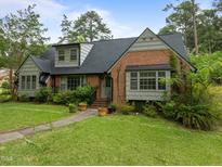 Charming brick home with mature landscaping and a well-maintained lawn on a sunny day at 3516 Swift Dr, Raleigh, NC 27606