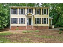 Charming two-story home with black shutters and a brick foundation, nestled among lush trees at 3517 Eden Croft Dr, Raleigh, NC 27612
