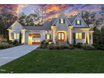 Inviting two-story home featuring a manicured lawn, double-door entryway, and attached carport at 387 Riverstone Dr, Pittsboro, NC 27312