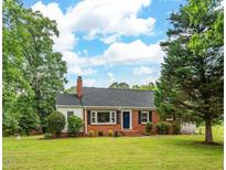 Charming brick ranch-style home with a welcoming front yard and mature trees offering shade at 4703 Pleasant Green Rd, Durham, NC 27705