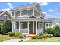 Charming two-story home featuring a welcoming front porch with classic white columns and lush landscaping at 500 Weaver Mine Trl, Chapel Hill, NC 27517