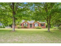 Charming brick home featuring a well-manicured lawn and beautiful mature trees offering shade at 5405 Doemont Dr, Apex, NC 27539