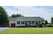 Charming one-story home features a welcoming front porch and well-manicured lawn, red garage door, and black shutters at 56 Sugarhill Dr, Zebulon, NC 27597