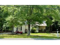 Charming single-story home with a covered porch, surrounded by mature trees and a red motorcycle at 981 Leasburg Rd, Roxboro, NC 27573