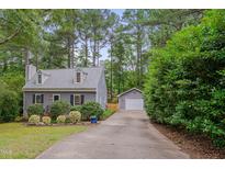 Charming gray home with dormer windows, a detached garage, and a long driveway lined with mature trees at 1302 Valley Run Dr, Durham, NC 27707