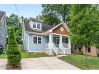Charming two-story home with light blue siding, a welcoming front porch and beautiful landscaping at 1920 Hart St, Durham, NC 27703