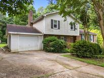 Traditional two-story home with a brick chimney, a garage, and mature landscaping at 204 Chatterson Dr, Raleigh, NC 27615