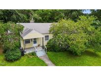 Charming yellow home with mature landscaping and a welcoming front porch, perfect for enjoying the outdoors at 212 Plum St, Burlington, NC 27215