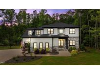 Stunning two-story home featuring stone and white siding, manicured landscaping, and a warm, inviting entrance at 310 Hidden Lake Dr, Youngsville, NC 27596