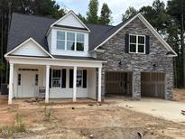 Charming new two-story home boasts stone accents, black shutters, a two-car garage, and a covered front porch at 400 Abingdon Farms Dr, Selma, NC 27576