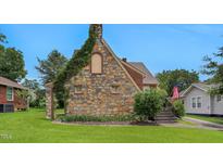 Charming stone and brick house with an American flag, beautiful lawn, and manicured landscaping at 407 Hillcrest Ave, Burlington, NC 27215