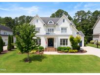 Charming two-story white home boasting a manicured lawn, lush landscaping, and classic architectural details at 4729 Adler Pass, Raleigh, NC 27612