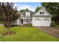 Charming two-story home with a well-manicured lawn, flowering plants, and a two car garage at 8116 Mosby Way, Willow Springs, NC 27592