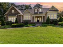 Charming two-story home featuring stone accents, manicured landscaping, and inviting front porch under a colorful sunset sky at 1096 Silverleaf Dr, Youngsville, NC 27596